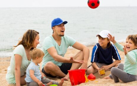 Happy family playing with ball at sandy beach